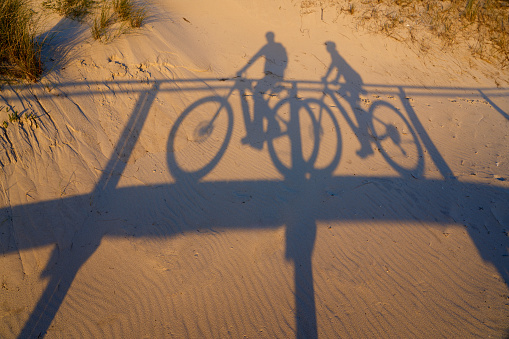 shadow of a cycling couple on the golden sand beach of Aveiro, Portugal
