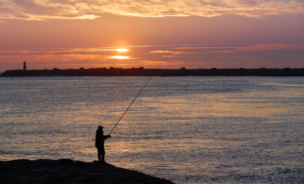 fisherman as silhouette in sunset at the Atlantic coast near Aveiero, Portugal