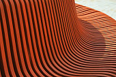 Brown wooden curved slats. Bench element, architectural design of building exterior. Abstract background.