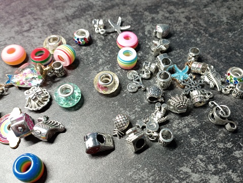 Many small beads are scattered on the surface of the table, the color of black concrete. Colorful and colorful beads for creating handmade bracelets.