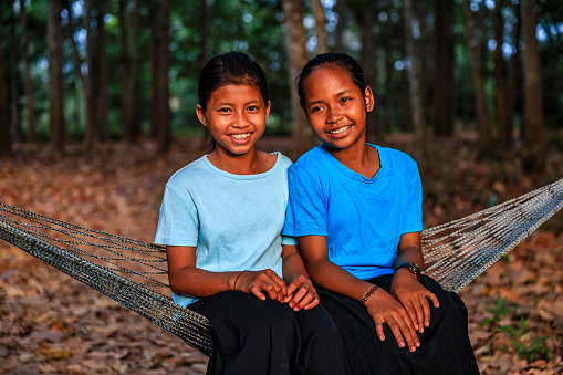 Two Cambodian young girls sitting on hammock in small village near Siem Reap, Cambodia