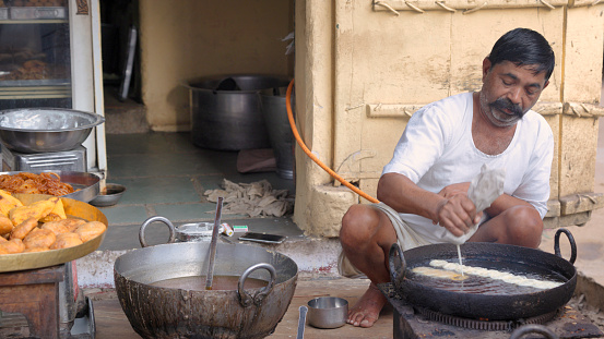 Indian street seller preparing a sweet - jalebi in Jaipur. Jaipur is known as the Pink City, because of the color of the stone exclusively used for the construction of all the structures.