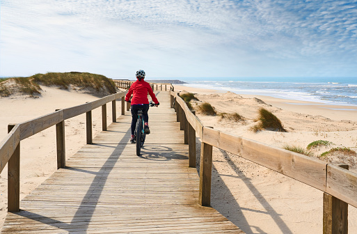 happy active senior woman cycling  at the beach of the atlantic coast of Aveiro, Portugal