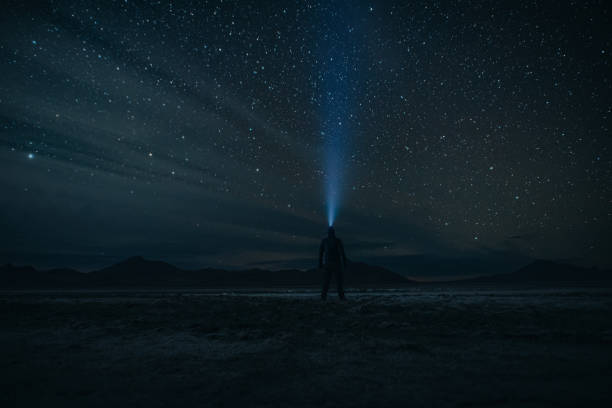 istock Man with a headlamp looks at the stars while outside at night 2148972473