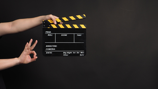 hands is holding clapper board or movie slate.It is used in video production and film industry on black background.