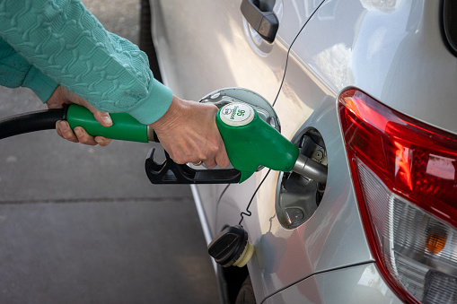 Filling up with expensive gasoline mixed with bio ethanol at a gas station with a filling nozzle in the gasoline tank of the passenger car