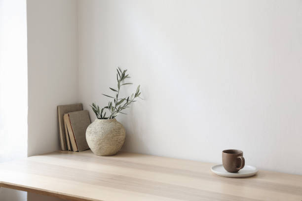 istock Breakfast, scandi indoor interior still life. Minimal home design concept. Beige ceramic vase with olive tree branches. Cup of coffee, tea on wooden table, desk with old books, empty beige wall mockup 2148977291