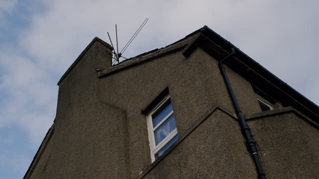 Low angle view of building exterior with chimney on the side and old television antenna on the roof