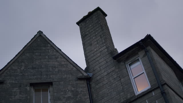 View of a traditional old stone house in England. Low angle shot of building exterior with.
