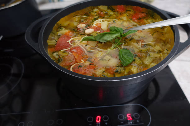 Pistou soup being cooked in a casserole dish on a ceramic hob