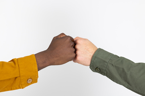 Close-up portrait shot of two hands fist-bumping each other. The hand on the left belongs to a young black man and the one on the right belongs to a young Asian man.

Videos are available similar to this scenario.