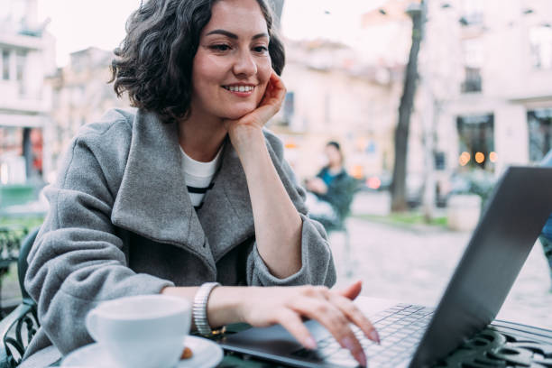 istock Young woman using laptop at a sidewalk cafe. 2148979864