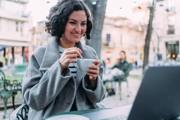 istock Young woman using laptop at a sidewalk cafe. 2148979870