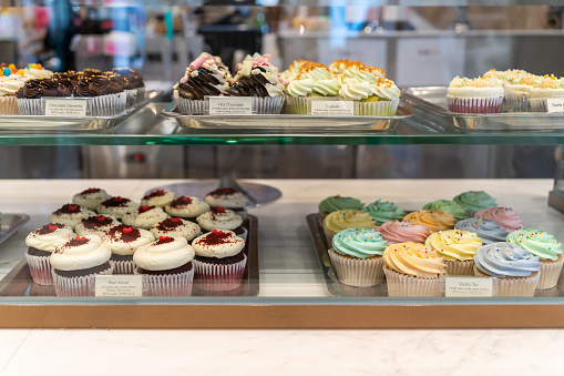 Various types of colorful cup cakes selling in the bakery shop.