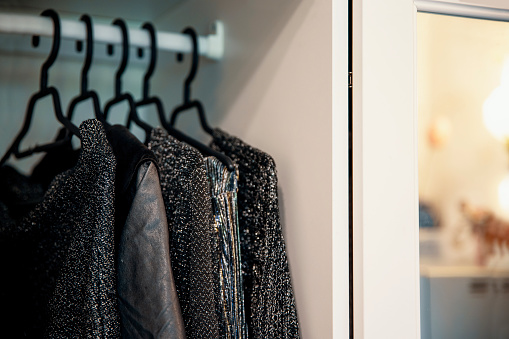 Glittering black elegant clothes hanging in the closet. Copy space