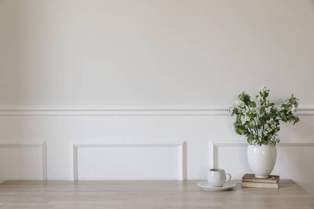 istock Ceramic vase with blooming apple tree branches. Cup of coffee, tea on wooden table, desk with old books. Scandi home interior. Spring breakfast still life. White wall mockup, stucco decor. Copy space. 2148983057
