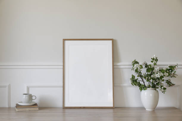 istock Springtime breakfast still life. Empty picture frame poster mockup. White ceramic vase with blooming apple tree branches. Cup of coffee, tea on wooden table, desk with old books. Scandi home interior 2148983062