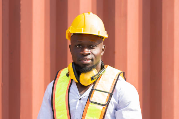 istock Male container yard worker loading containers box at commercial dock site. Male worker control loading container box from cargo freight ship for import export 2148983586