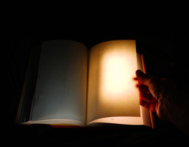 istock A person's hand opening a book as the page is brightly lit , signifying adventure, learning or the unknown 2148986890