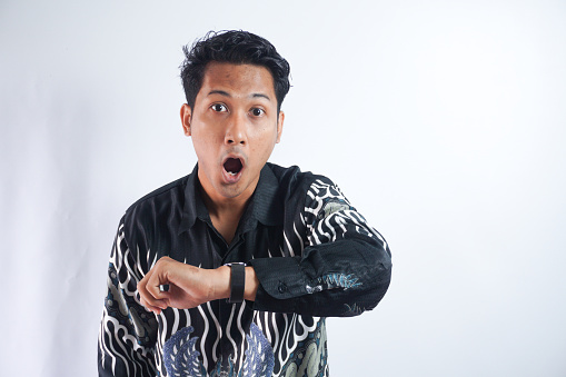 Shocked asian man in Batik shirt looking at watch