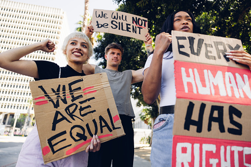 Young adult men and women marching together on strike against racism holding signs on cardboards for equal rights for everyone. Rally in the city of Los Angeles.