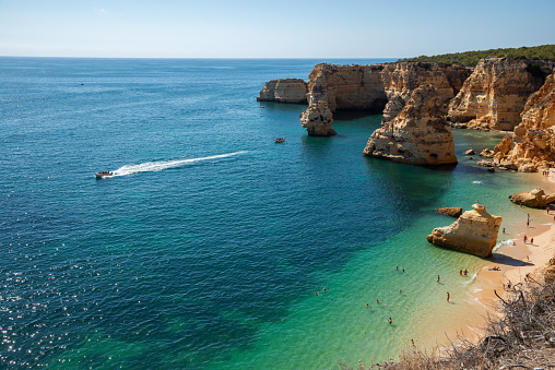 Stunning panoramic view of the ocean in Lagos, Algarve, featuring sailboats, a rocky coastline, and clear blue skies. Perfect for a peaceful day out.