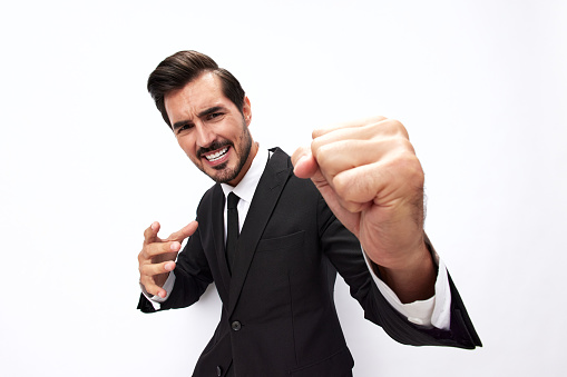 Portrait of a man in an expensive business suit close-up wide-angle lens pulling his hands to fight into the camera with his mouth open screaming his fists up on a white background, copy space. High quality photo