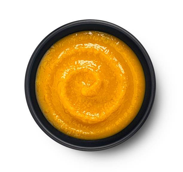 istock Pumpkin cream soup in black bowl isolated on white background, top view 2148995867