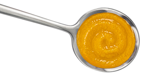 Pumpkin cream soup in spoon isolated on white background. Top view