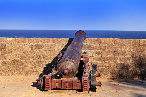 Beautiful blue sky and look like old time. movable sixteenth century Portuguese cannon made of metal and a wooden base. It's located on a bastion of Diu Fort, a tourist spot located in Diu India.j
