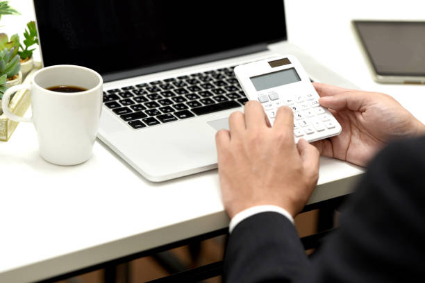 Hands of businessman calculating with calculator in front of laptop computer Hands of businessman calculating with calculator in front of laptop computer Life insurance calculator stock pictures, royalty-free photos & images