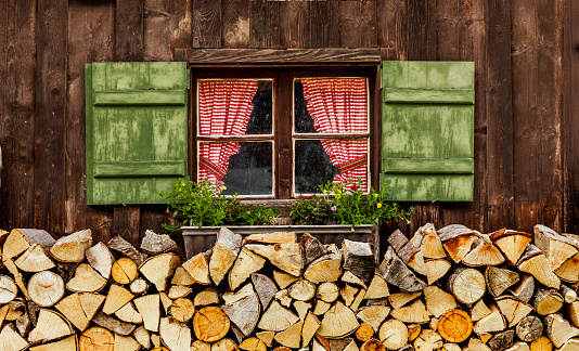 Window with green shutters and checkered curtains on an alpine hut