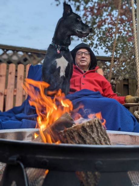 A man and his dog sit by a fire on a swing