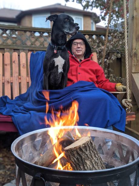 istock A man and his dog sit by a fire on a swing 2149000234
