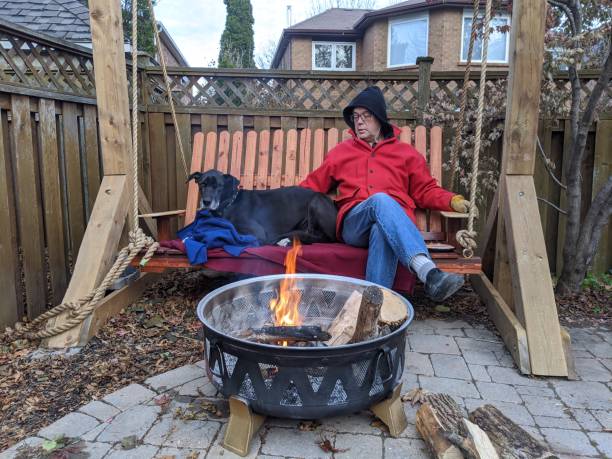 istock A man and his dog sit by a fire on a swing 2149000243