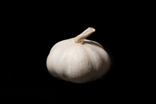 Garlic bulb on a black background. Unpeeled garlic bulb with tenderloin.