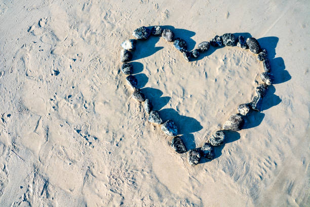 A heart made of rocks on a beach. The rocks are arranged in a way that forms a heart shape. The scene is peaceful and serene, with the rocks and sand creating a beautiful and calming atmosphere