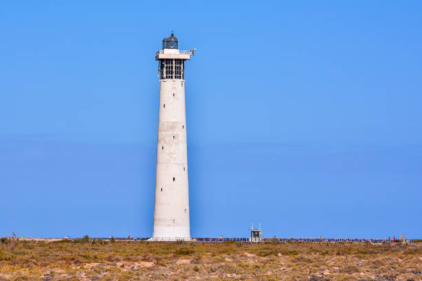 istock A lighthouse is standing in a field with a clear blue sky 2149002562