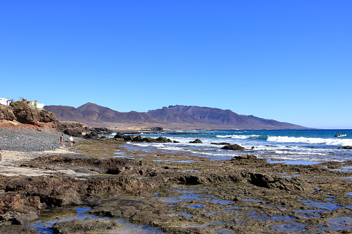 November 19 2023 - Puerto de la Cruz, Jandia, Fuerteventura in Spain: people at the rocky Playa de los Ojos - Los Ojos Beach