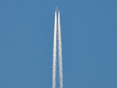 An airplane soars gracefully at cruising altitude, leaving behind a trail of white contrails against the backdrop of a clear, blue sky. The sleek silhouette of the aircraft stands out against the vastness of the heavens, symbolizing the wonder of human innovation and the boundless possibilities of flight. As the contrails stretch across the sky, they trace the path of the plane's journey, a fleeting reminder of the marvels of modern travel amidst the beauty of the natural world.