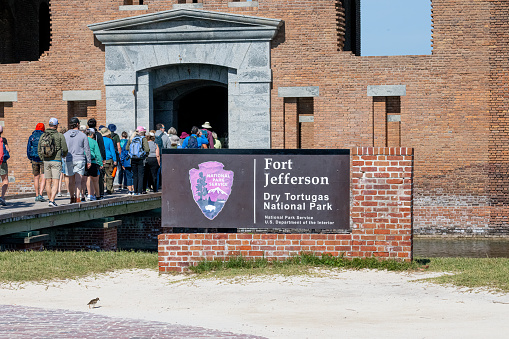 A group of people pass the sign of Fort Jefferson as they enter the Sally Port to enter the fort in the, Dry Tortugas National Park, Florida, USA.
