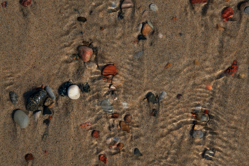Multicolored sea pebbles on sand through seawater, Baltic Sea, Curonian Spit, Kaliningrad region, Russia