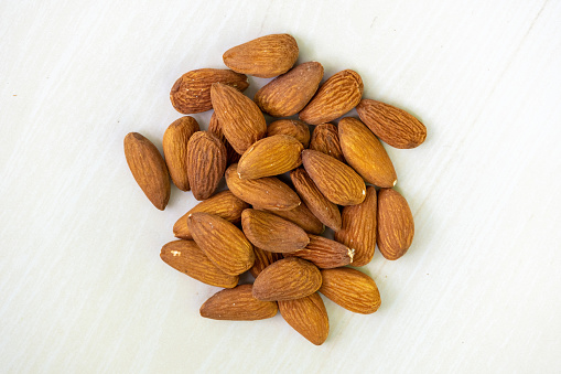 Almonds isolated on a wooden background. Almond nuts are a healthful food. Locally in Bangladesh, it is called Kath Badam.