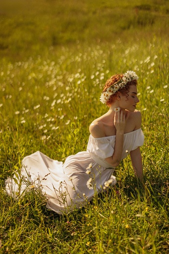 Beautiful girl in a field with a bouquet of flowers and a wreath
