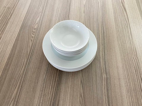 Porcelain plates and bowls on the wood table. Group of clean plates and bowls