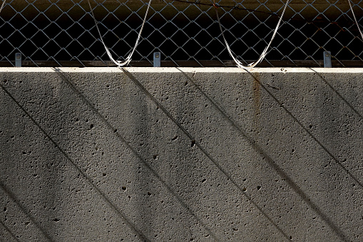 Razor wire casting shadows on concrete