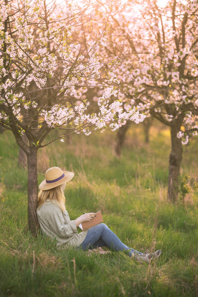 istock Female writer looks for inspiration to write her book while contemplating in spring blooming orchard 2149010125