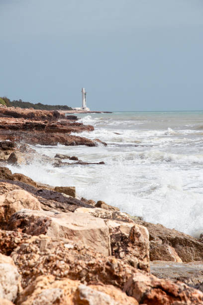 Raging sea crashing on the rocks. In the background you can see the lighthouse, which is very characteristic for its modern shape. Located on the coast of Alcossebre (Castellón de la Plana).