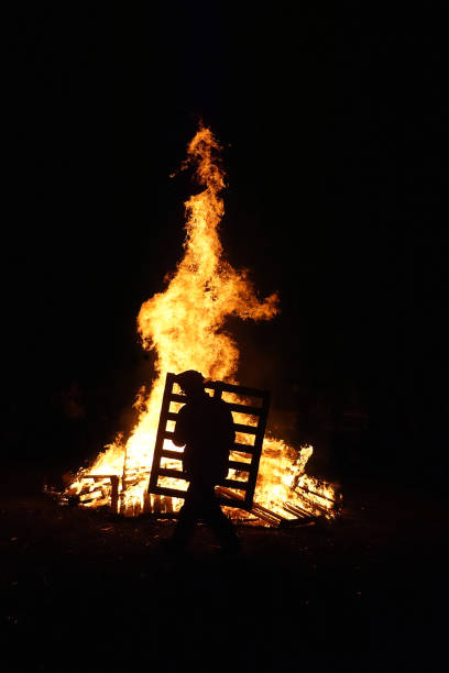 istock Person adding Burning Wooden pallet to bonfire 2149011740