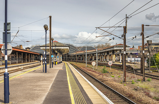York, UK.  April 14, 2024. View of a railway station with a lamp post in the foreground. The platform leads to 19th Century historic canopies and columns. In the distance are iron and glass arches.